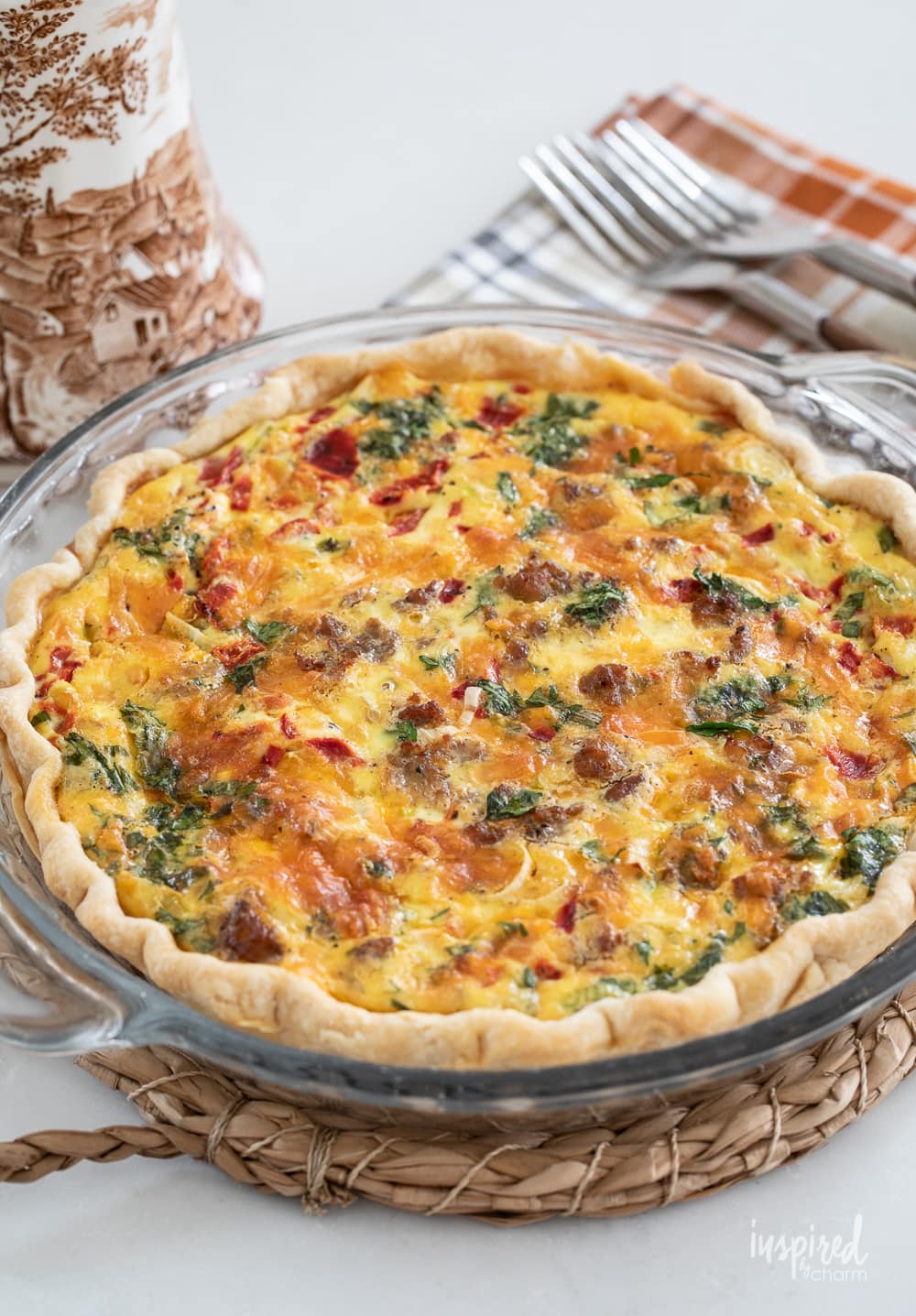 whole red pepper and sausage quiche in a clear pie plate.