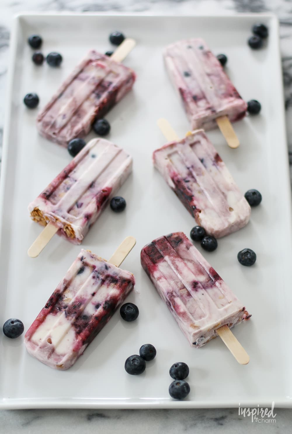 Blueberry Parfait Yogurt Popsicles on a large platter garnished with blueberries
