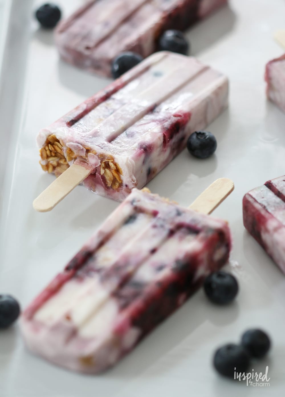 Blueberry Parfait Yogurt Popsicles on a large platter garnished with blueberries.