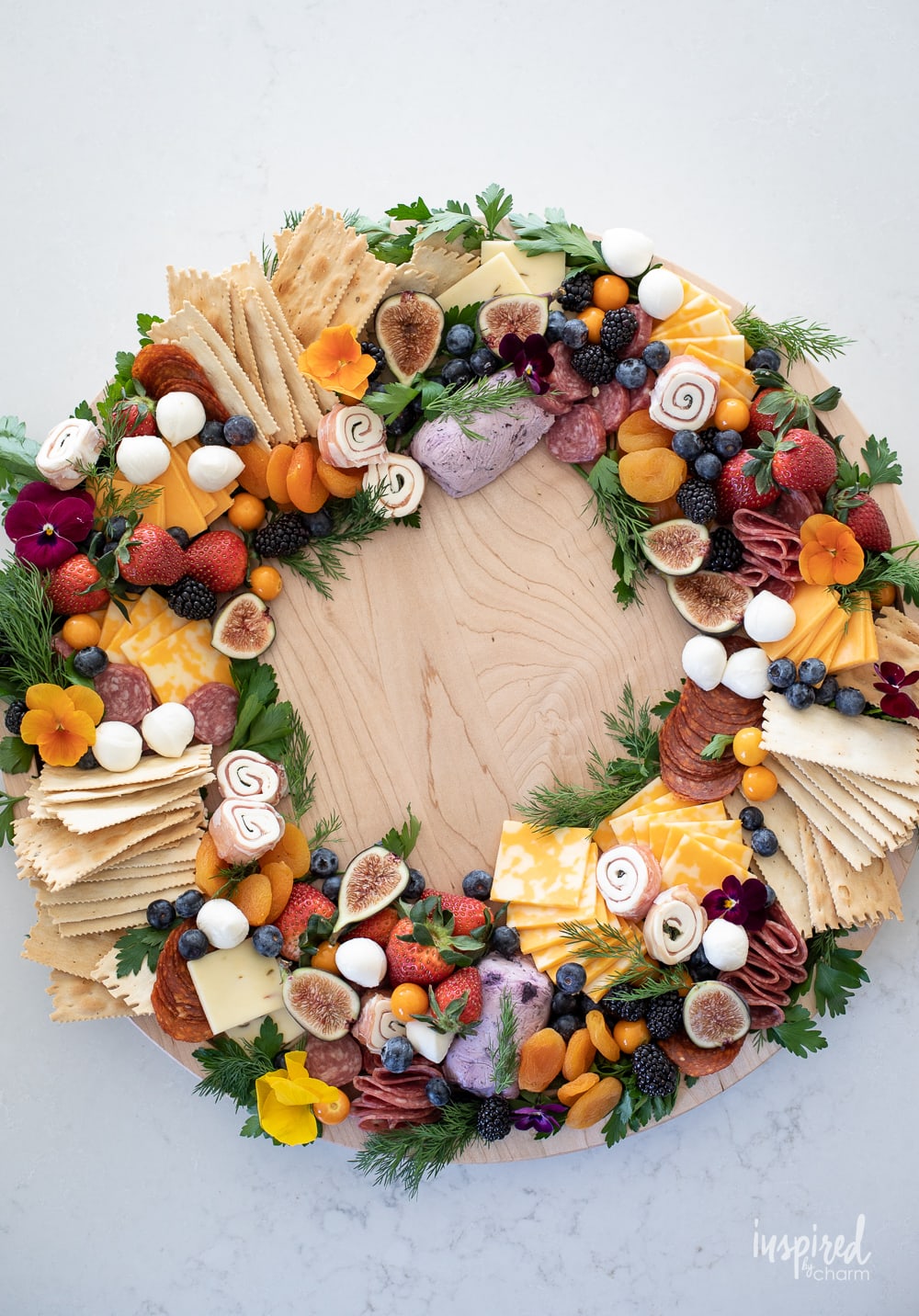 round charcuterie board shaped into a circle wreath filled with meats, cheese, fruits, and crackers.
