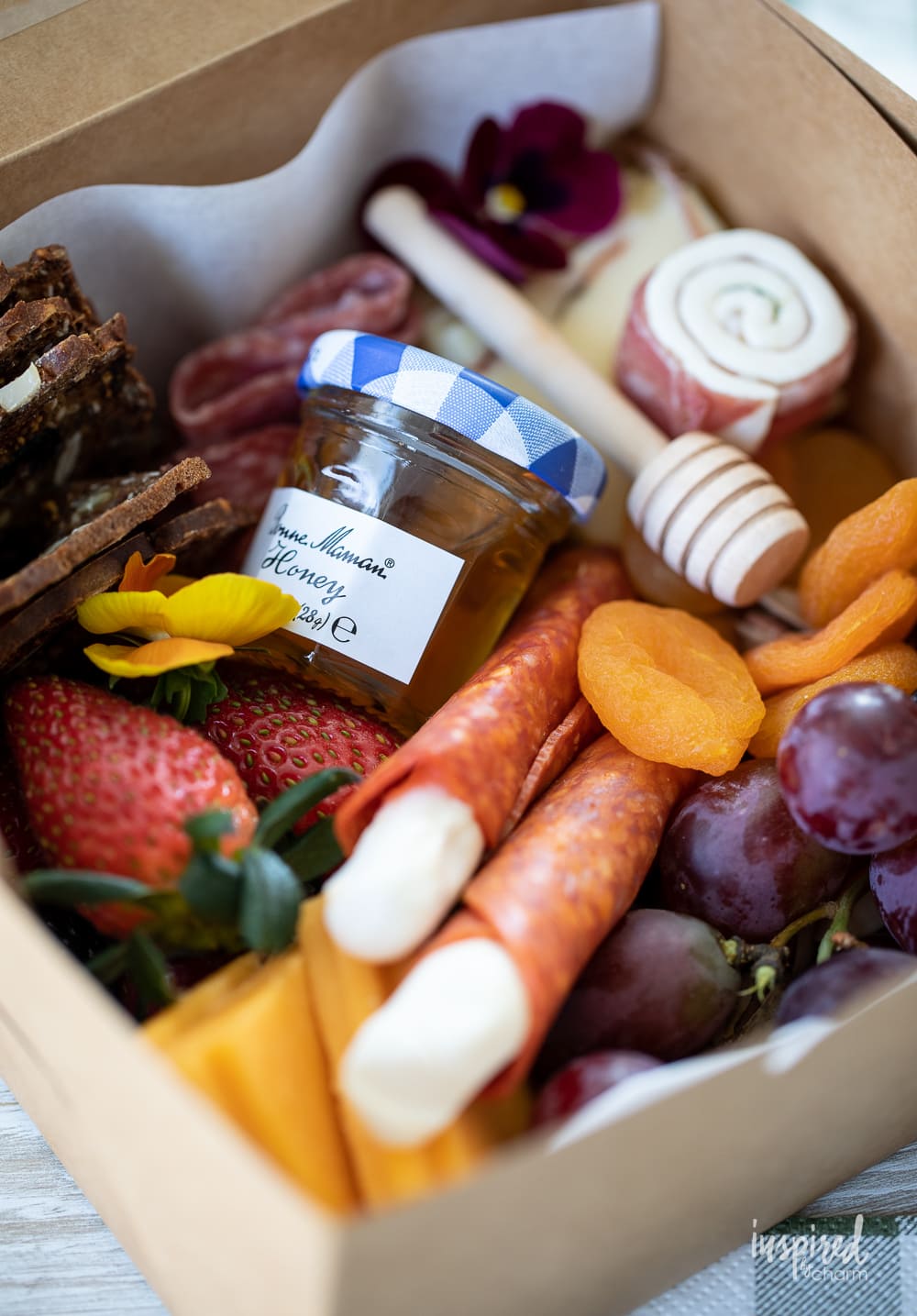 close up of a charcuterie box filled with meats, cheese, fruits, and more.