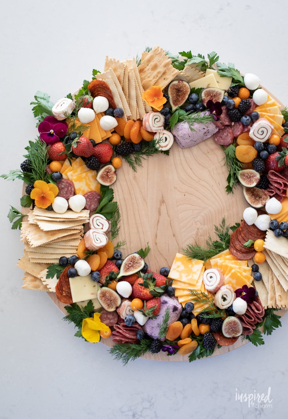 round wreath shaped charcuterie board piled with ingredients. 