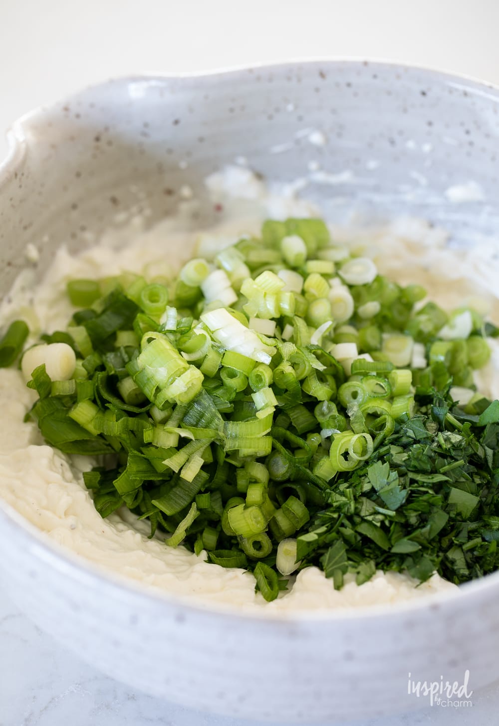 mixing green onion dip in a bowl.