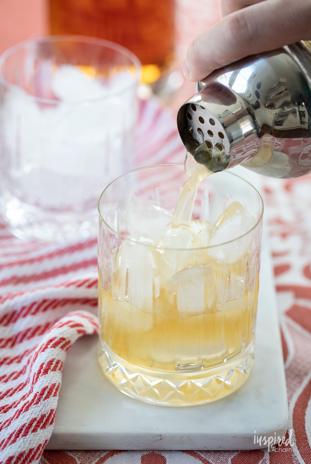 cocktail shaker pouring bourbon smash cocktail into rocks glass.