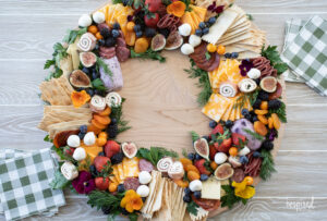 epic charcuterie board shaped into a circle wreath filled with meats, cheese, fruits, and crackers.