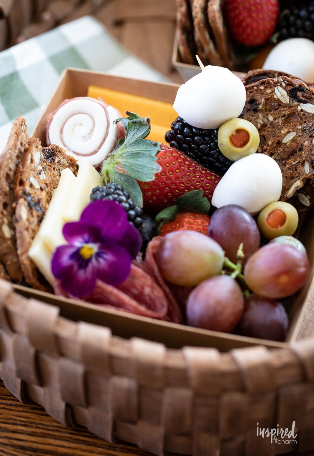 close up of two charcuteries box filled with cheeses, meats, fruits, and crackers.