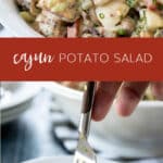 big white bowl of cajun potato salad with one serving on a small white plate.