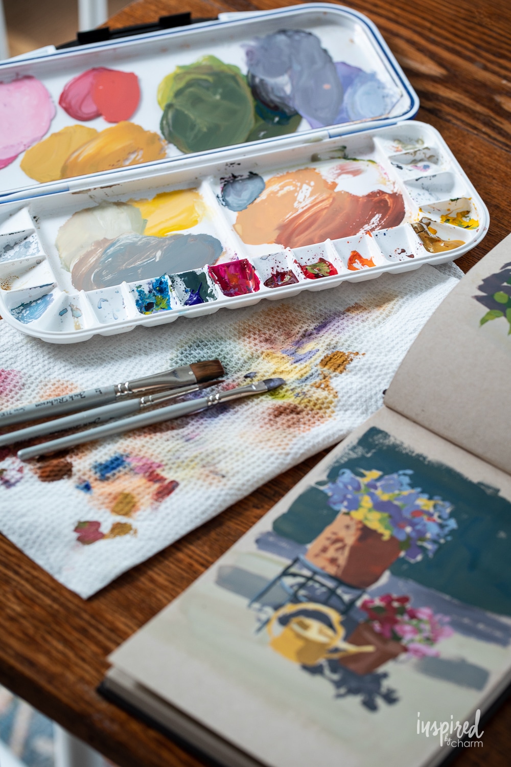 gouache painters palette with paint and a toned paper sketchbook.