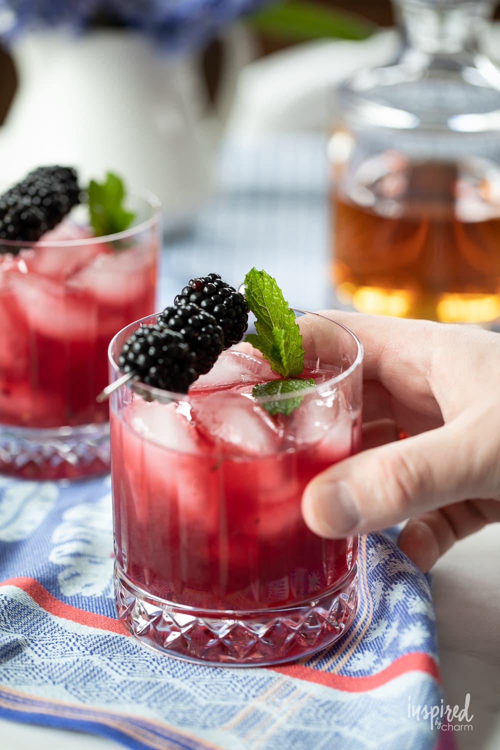 hand holding blackberry bourbon smash cocktail.