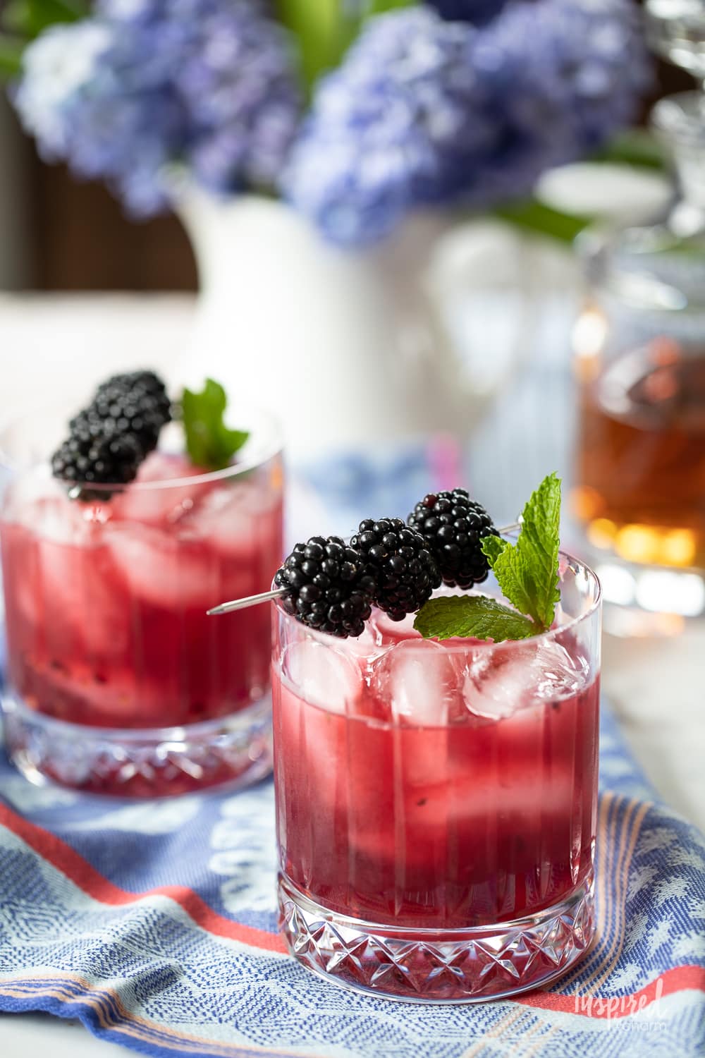 two blackberry bourbon smash cocktails with fresh blackberry garnish.
