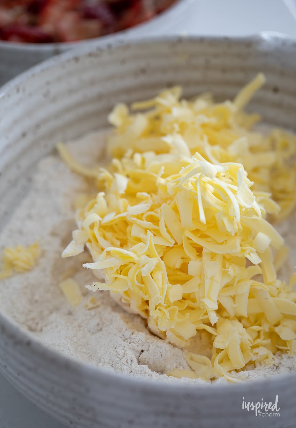 frozen butter grated in a bowl with dry ingredients.