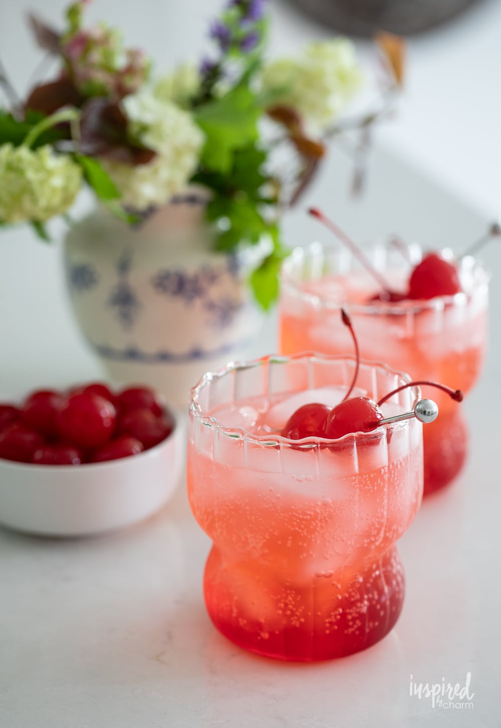two dirty shirley cocktails in glasses garnished with cherries. 