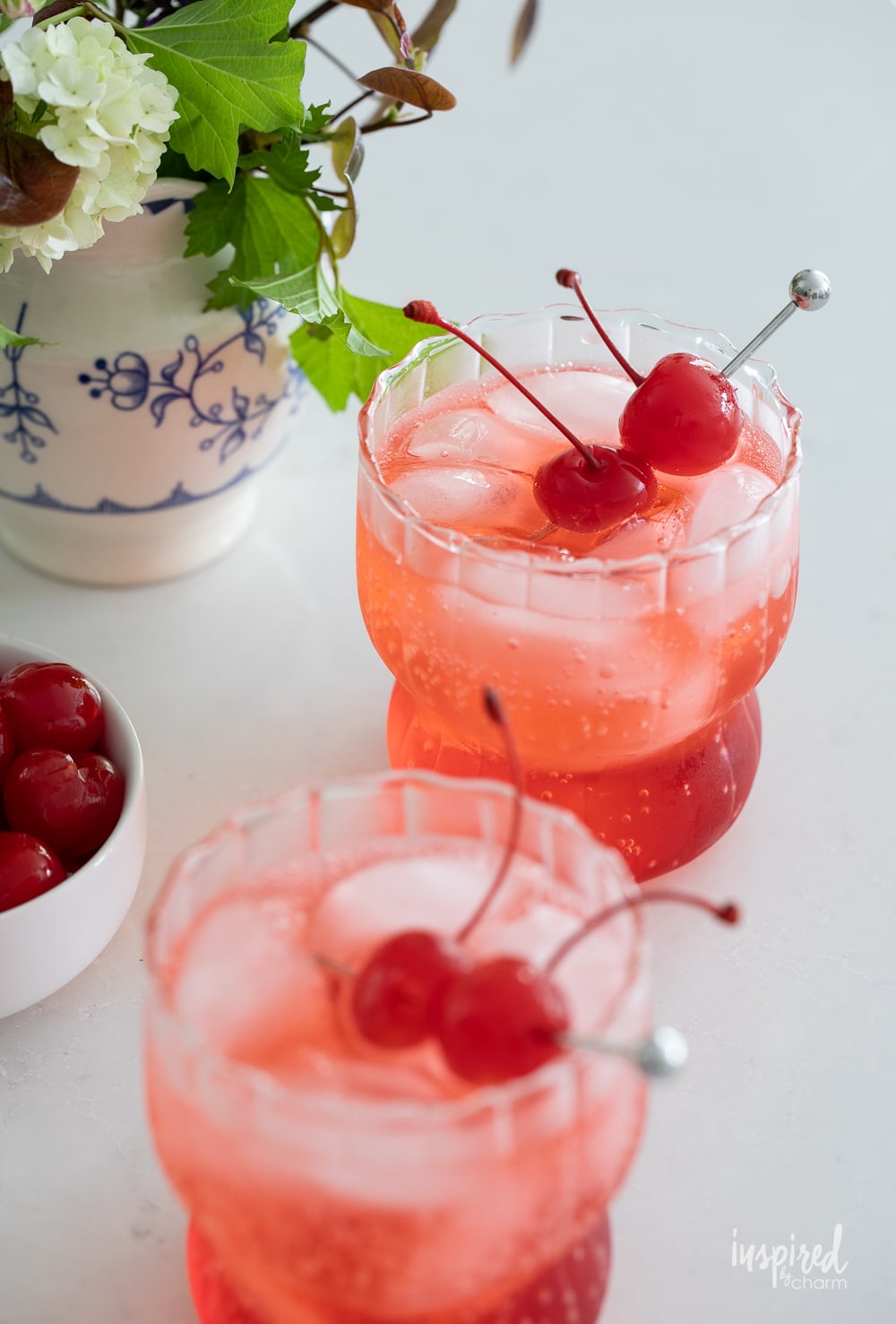 two dirty shirley drinks in glass with a maraschino cherry garnish. 