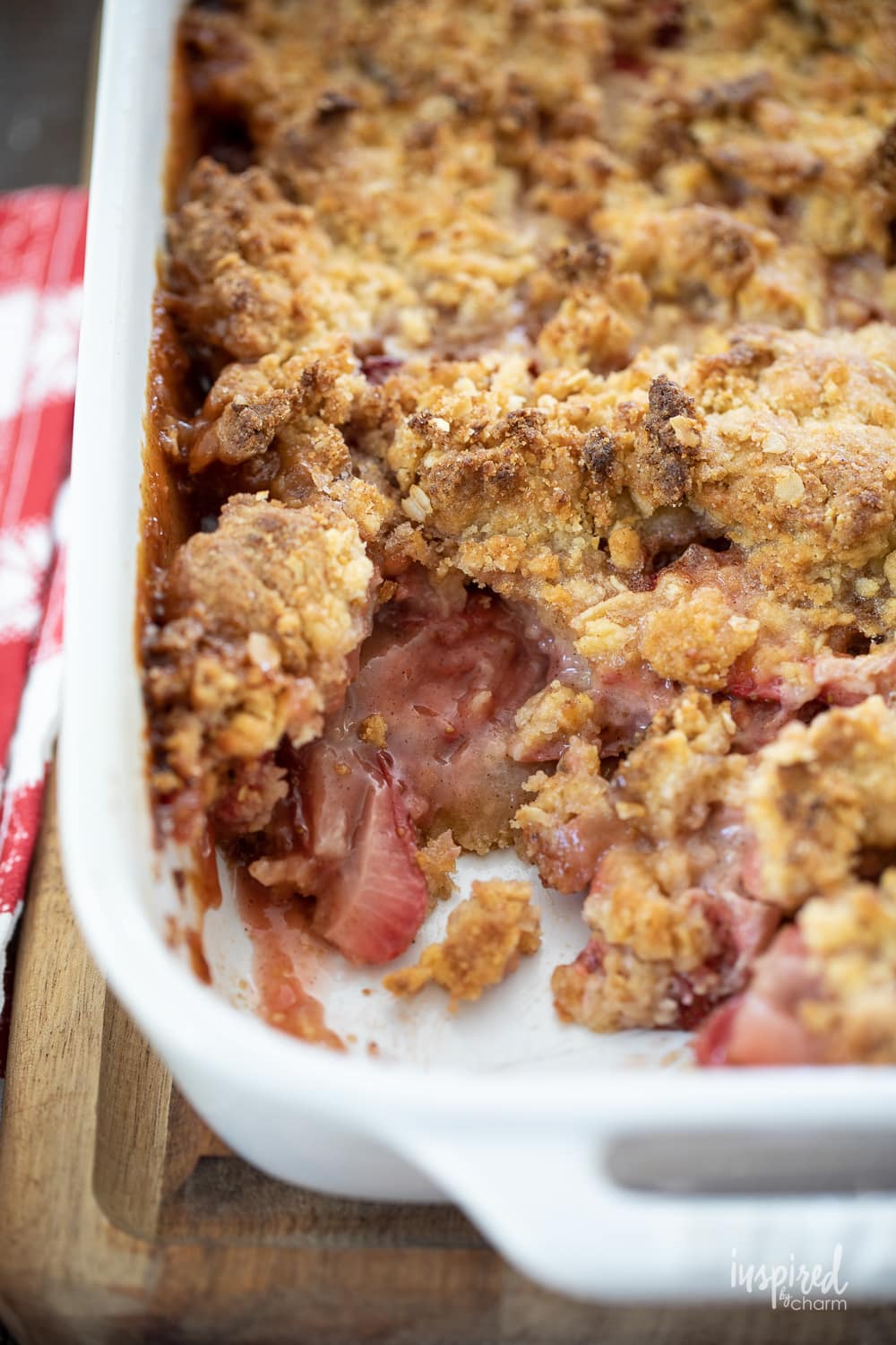 strawberry cobbler in a white baking dish with a scoop missing. 