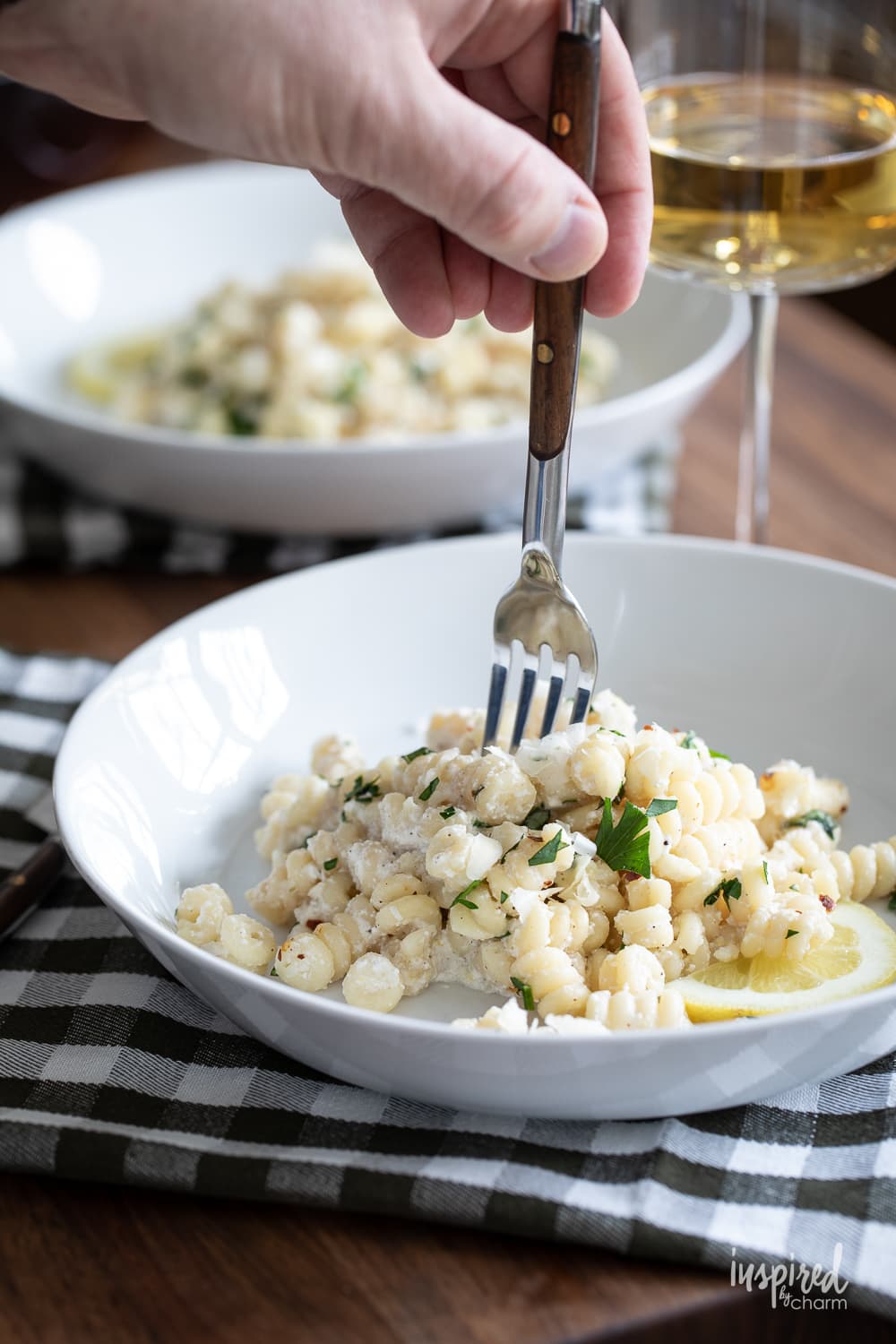 hand with fork into a bowl of lemon ricotta pasta.