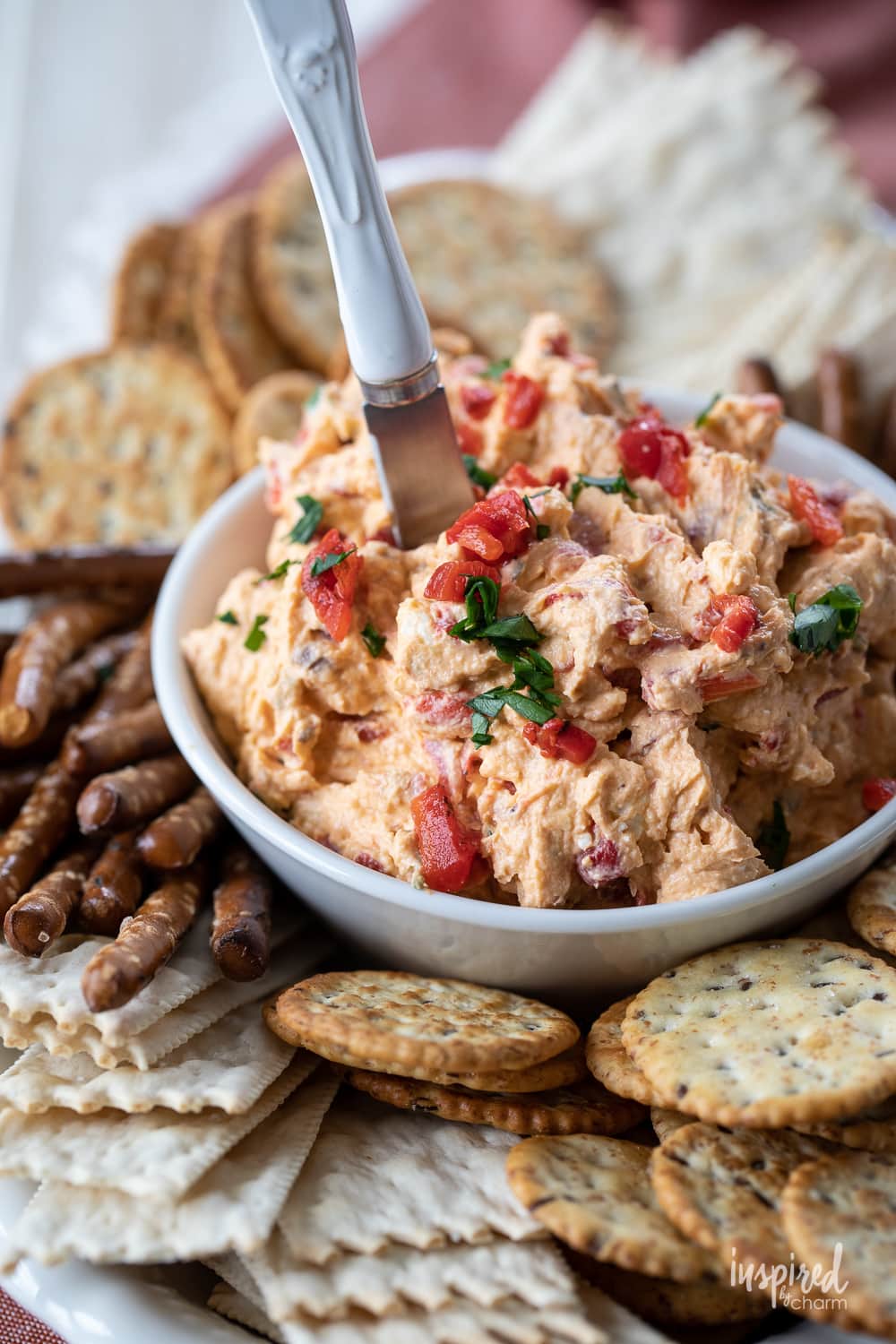 easy roasted red pepper dip in a bowl with pretzels and crackers.