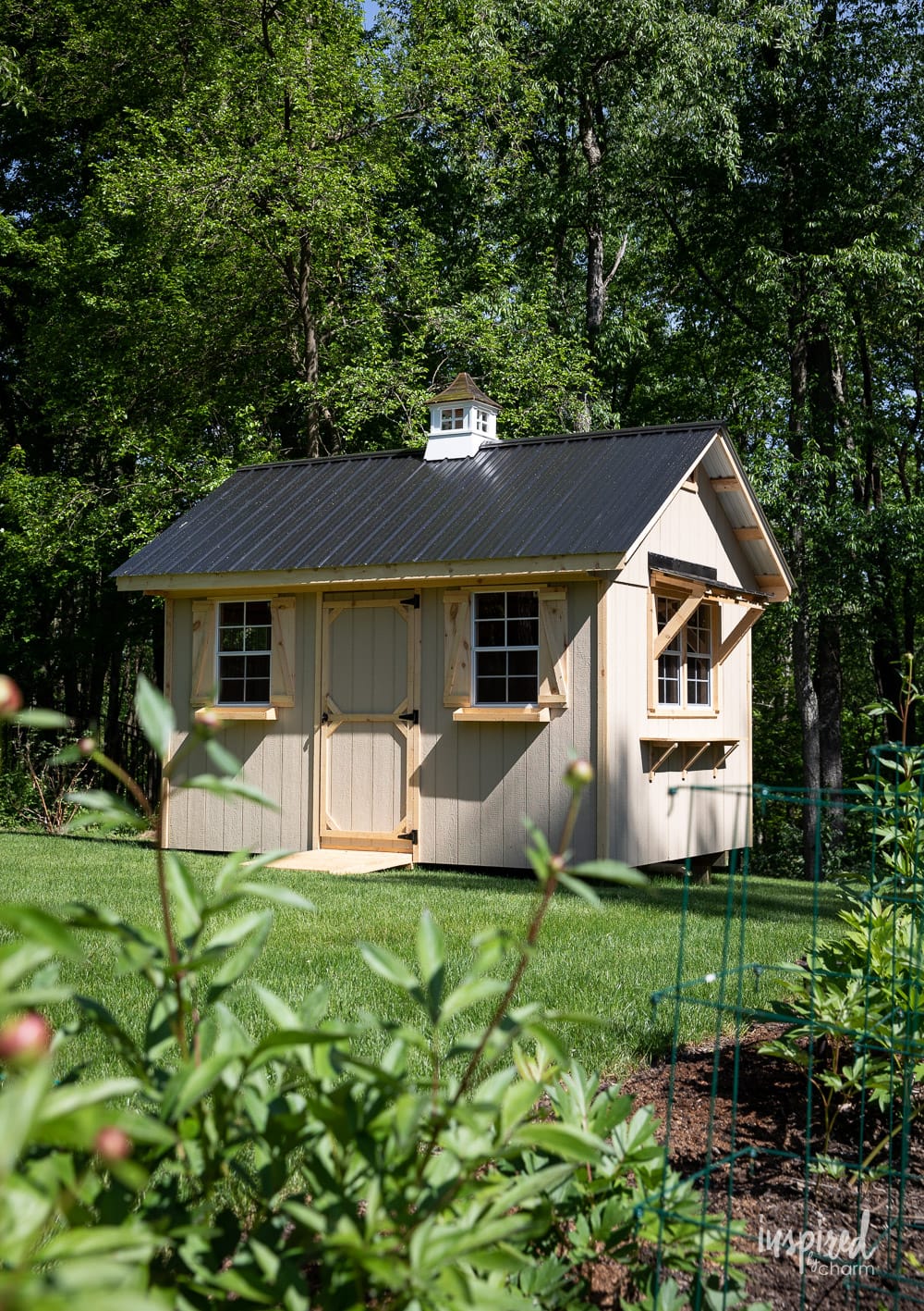 a shed with a black roof sitting in a backyard.