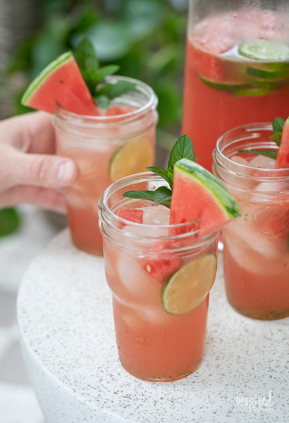 watermelon sangria in glasses with a hand picking up one glass.