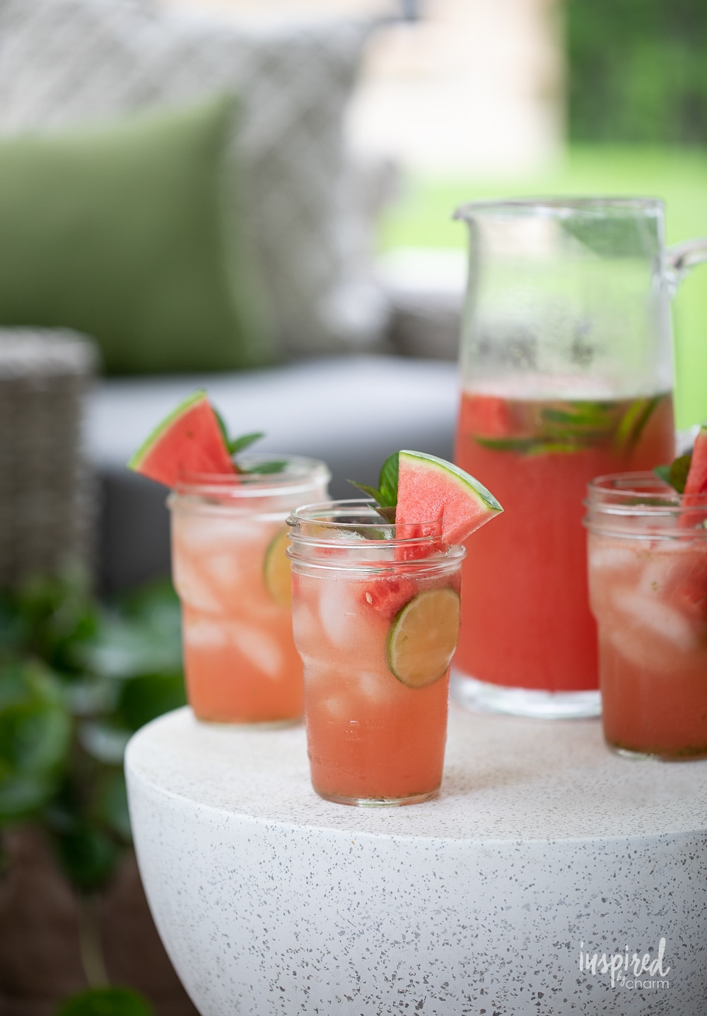 watermelon sangria in a pitcher and mason jar glasses on a white table outside. 