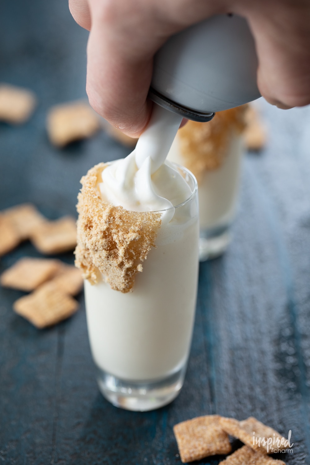 adding whipped cream to a Cinnamon Toast Crunch shot.