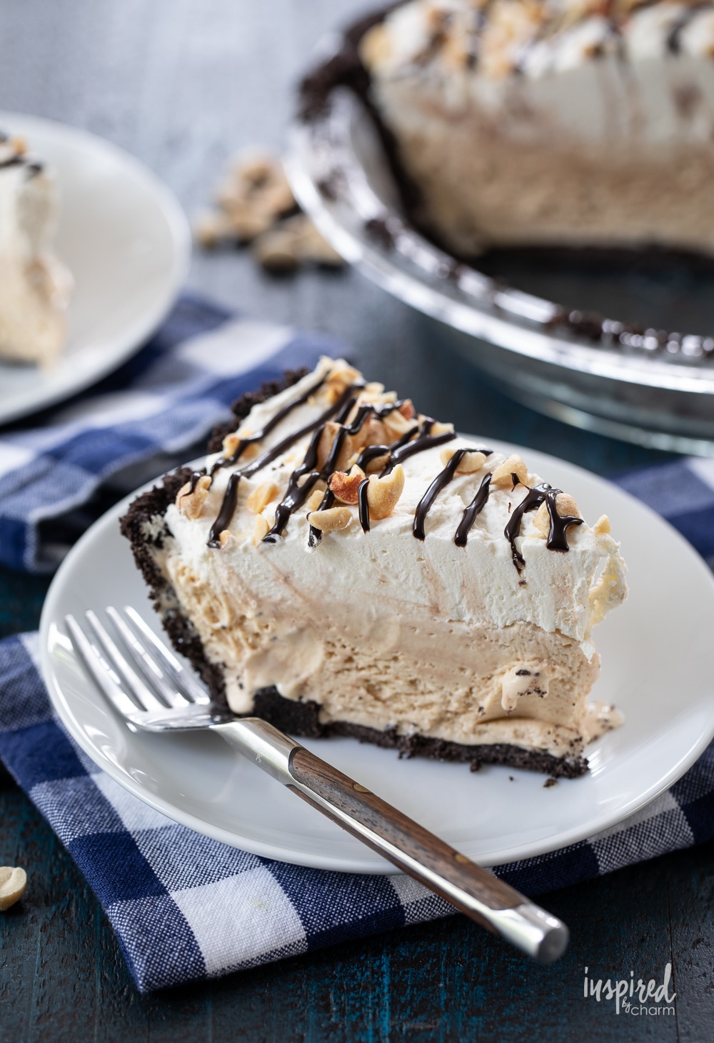 slice of peanut butter ice cream pie on a small white plate with a fork on gingham napkin.