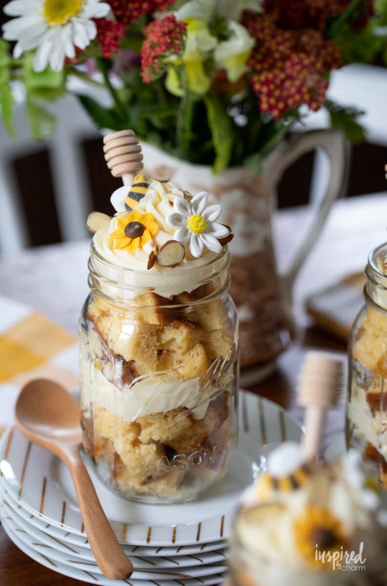 honey cake in mason jar layered with frosting and topped with edible flowers.