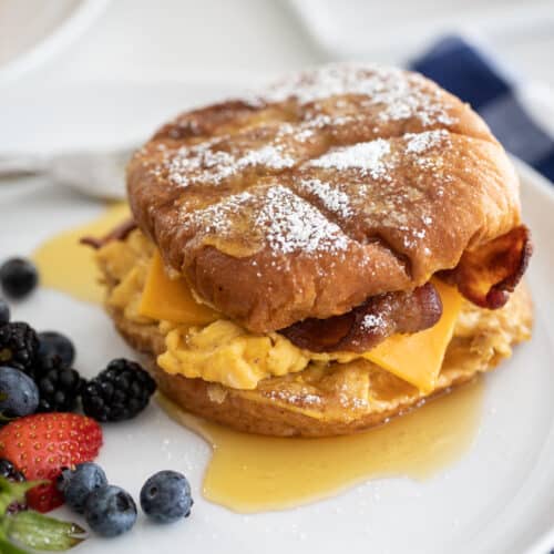up close french toast breakfast sandwich on a plate with berries.