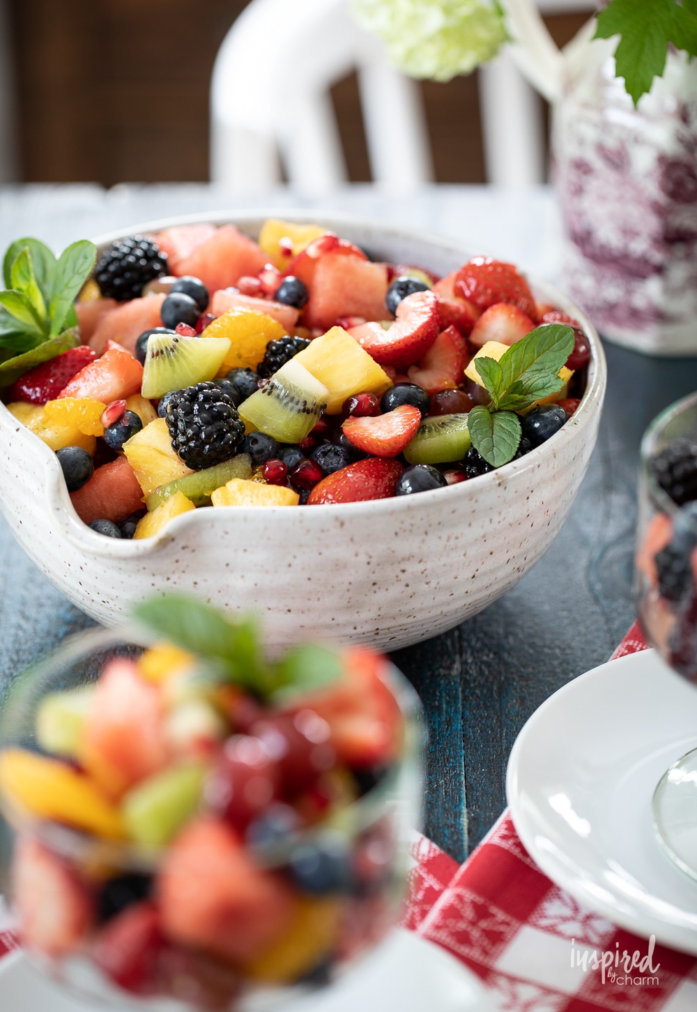 large bowl filled with colorful fruit salad and garnished with mint.
