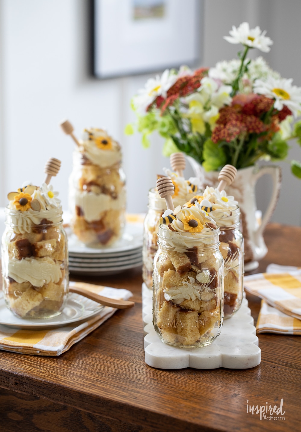 mason jar honey cakes display on a table with a flower arrangement.