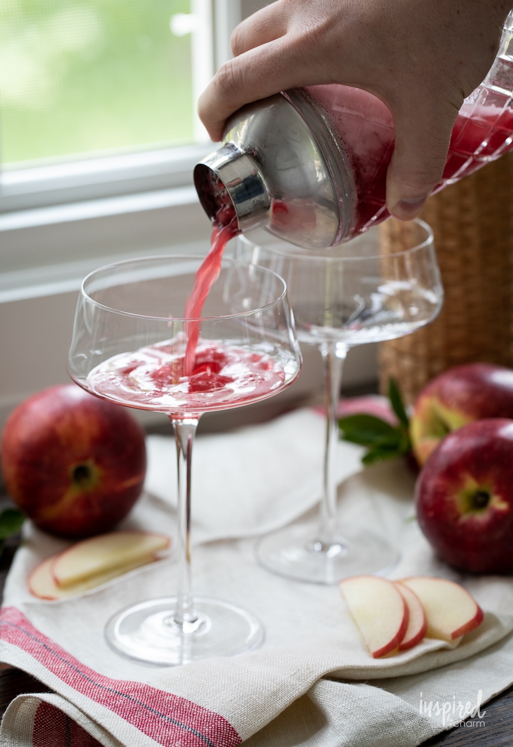 pouring washington apple cocktail from cocktail shaker into a martini glass.