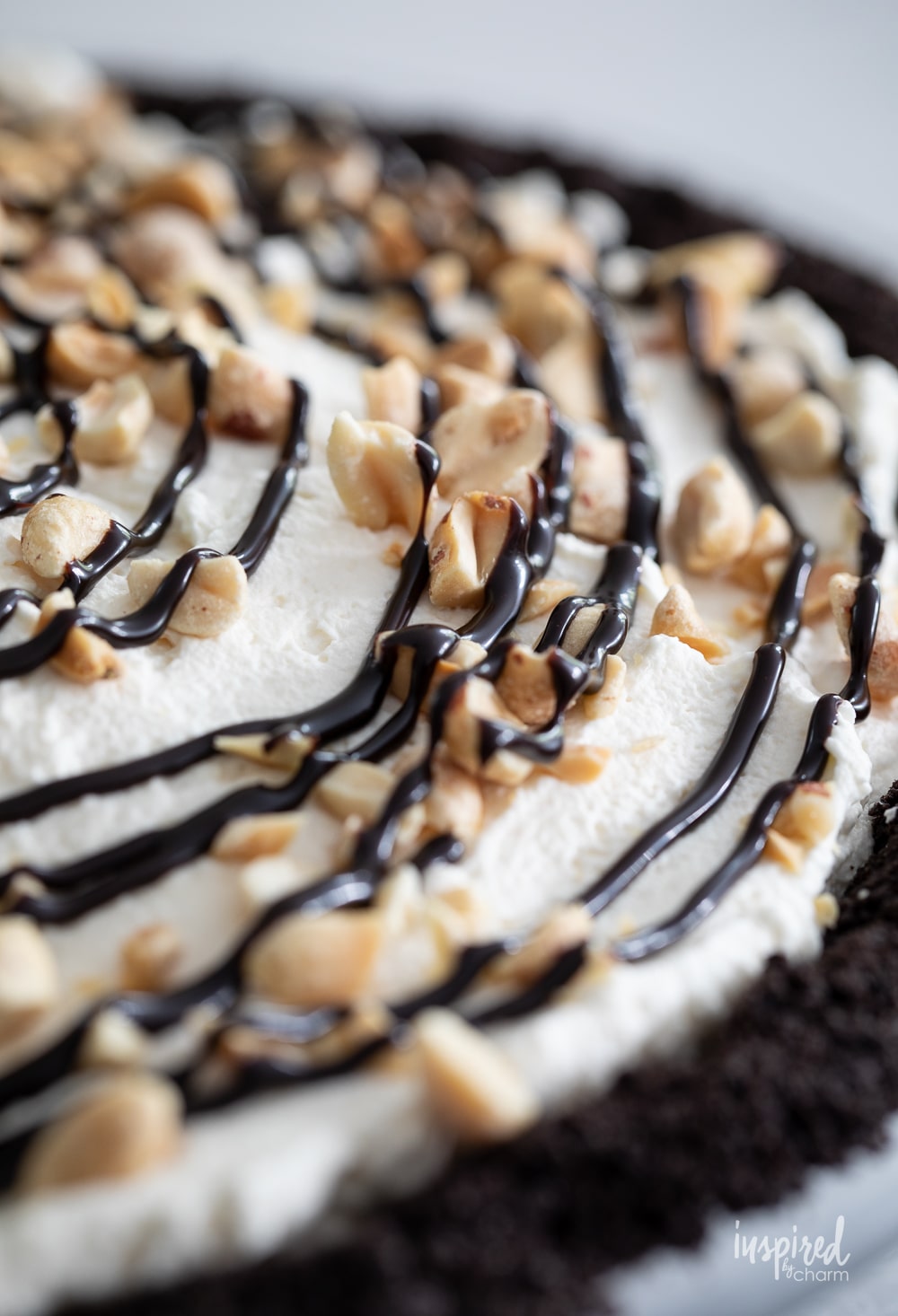 close up of the top of a peanut butter ice cream pie drizzled with chocolate and sprinkled with peanuts.