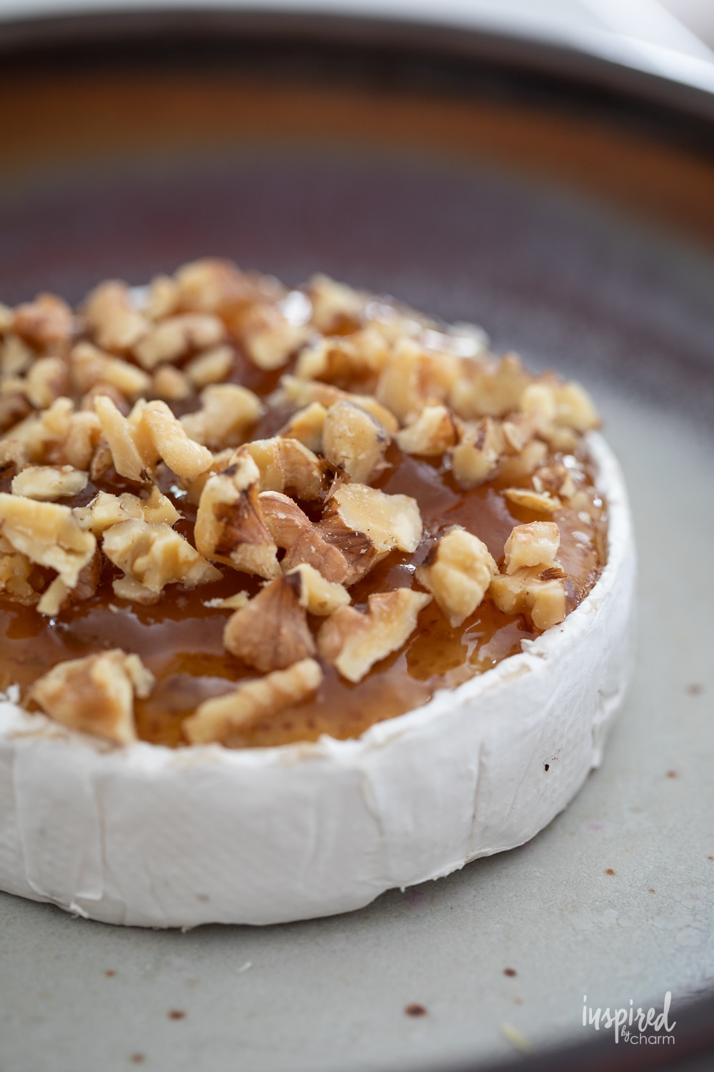 wheel of brie with jam and nuts sprinkled on top.