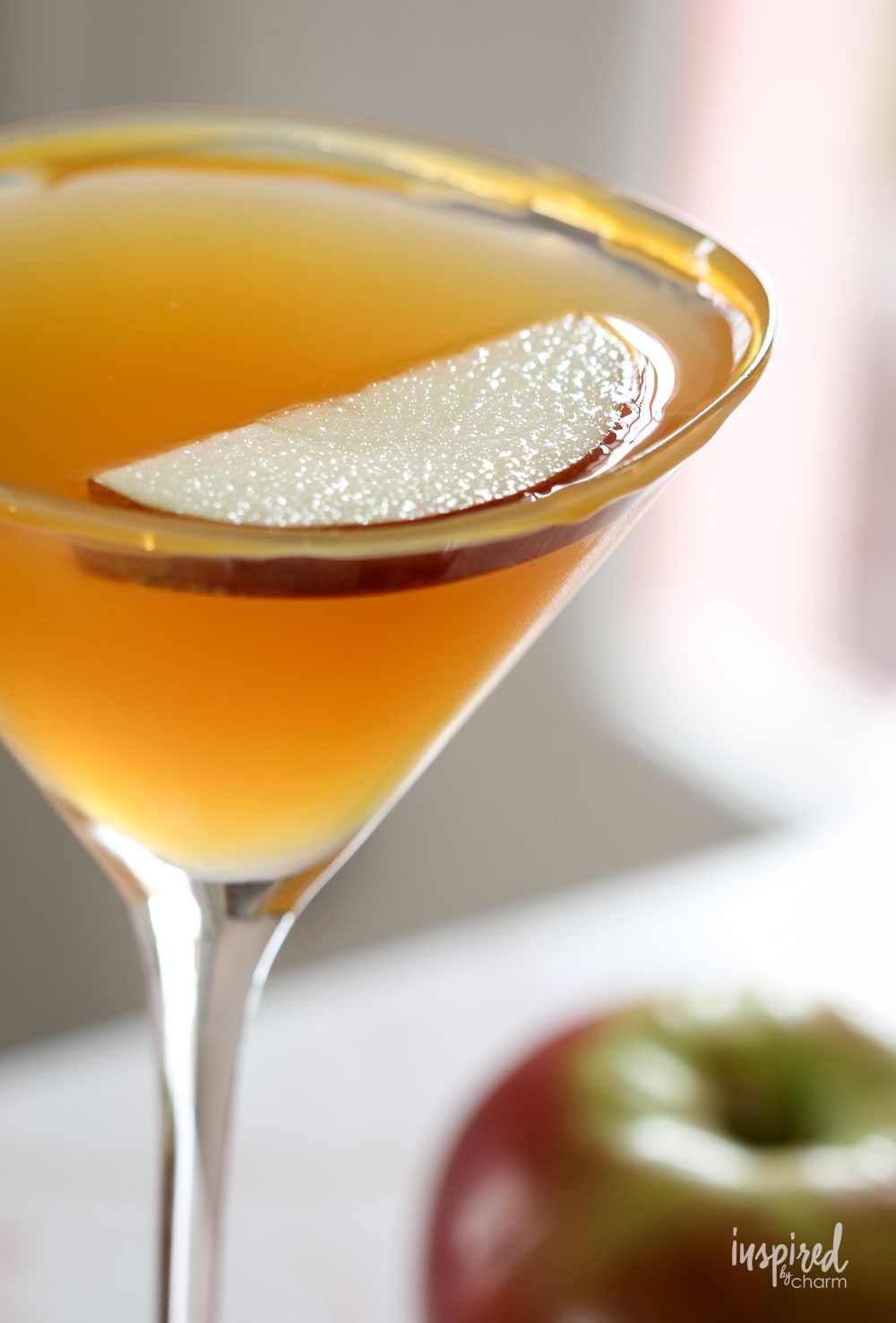 caramel apple martini in martini glass with caramel rim and apple slice garnish. 
