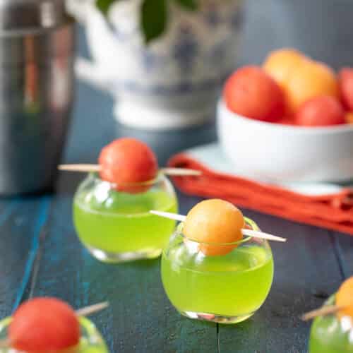 melon ball shots in small round shot glasses with melon ball garnish on top.