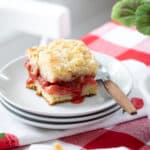 piece of strawberry rhubarb coffee cake on a stake of small white plates.