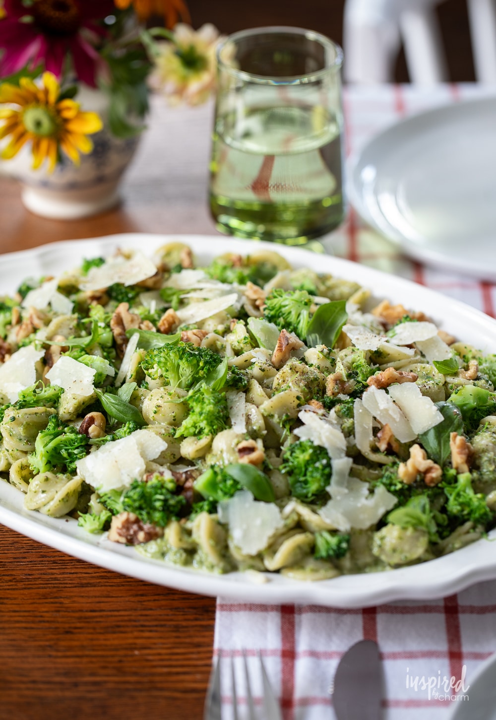 table with a big platter of broccoli pesto pasta on it. 