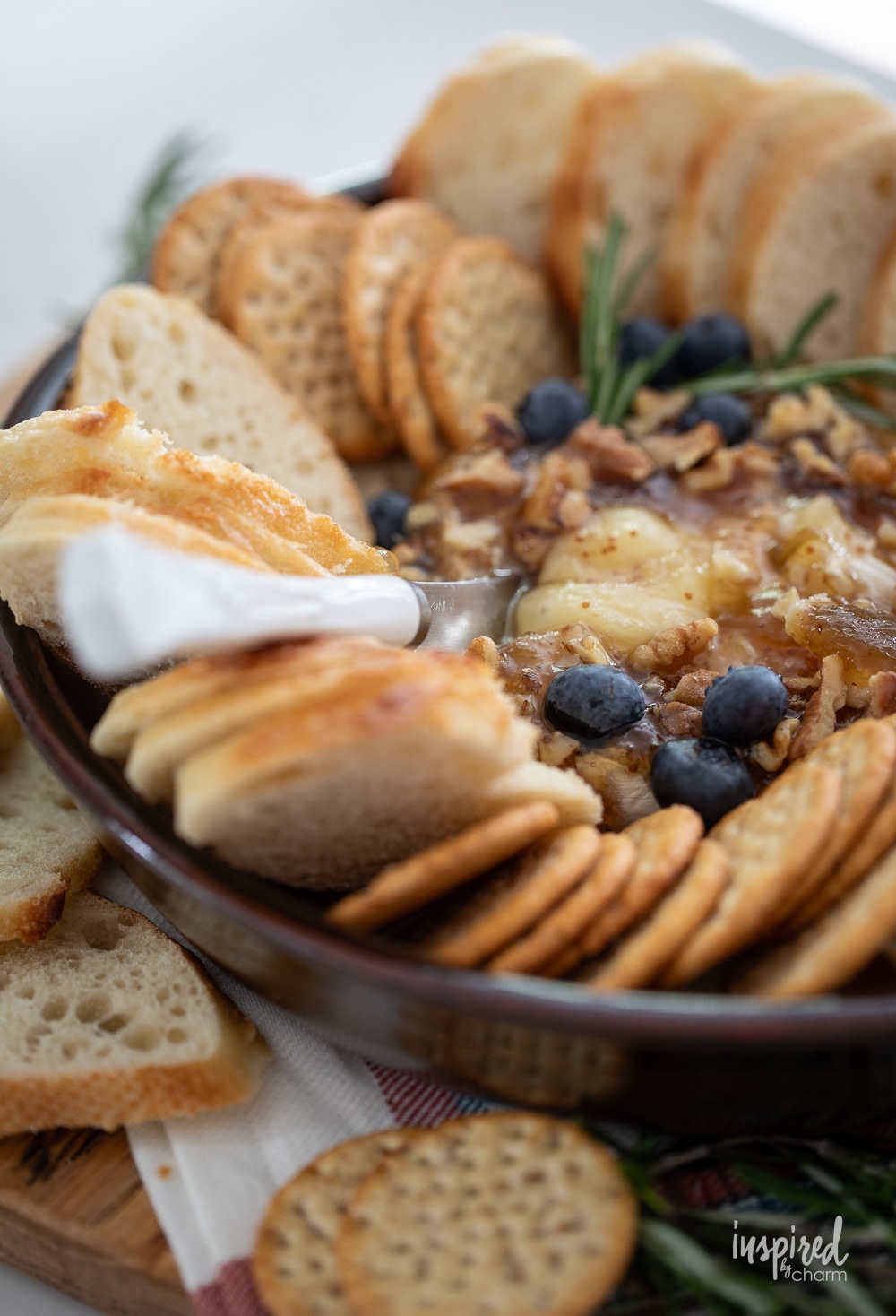 up close photo of baked brie with jam, blueberries, and nuts. 