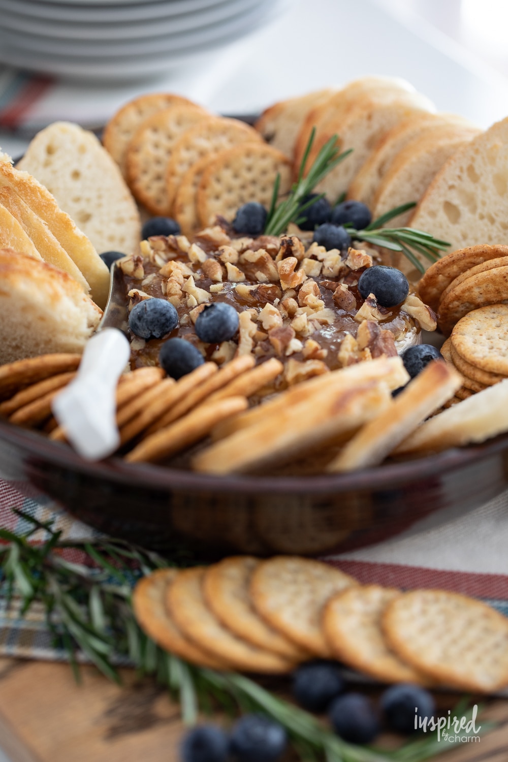 baked brie served with jam, crackers, and bread in a round dish.
