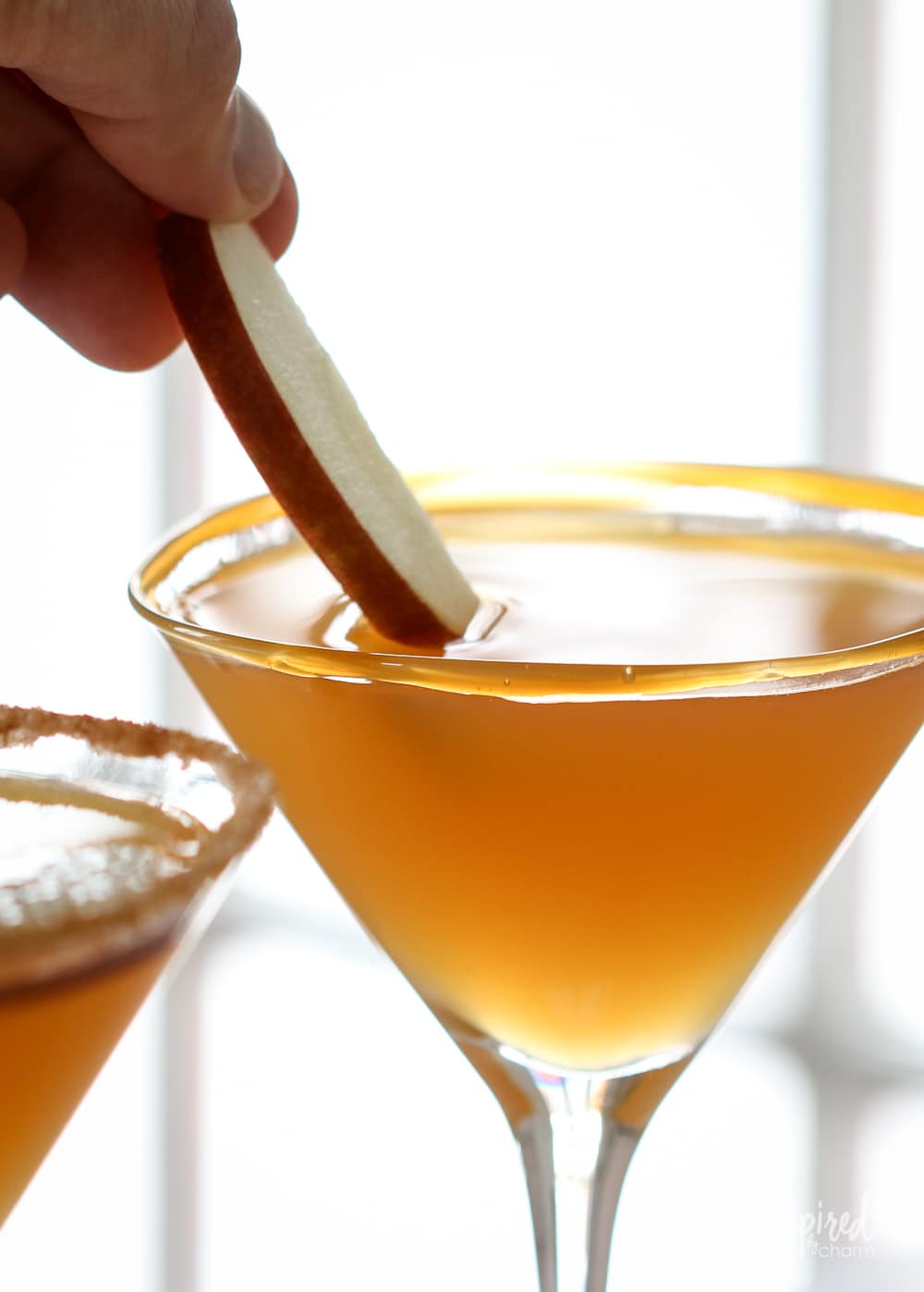 hand adding apple slice to caramel apple martini