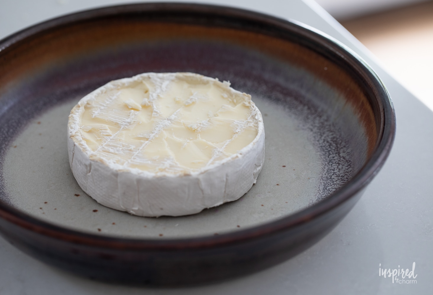 brie cheese wheel on a round baking dish. 