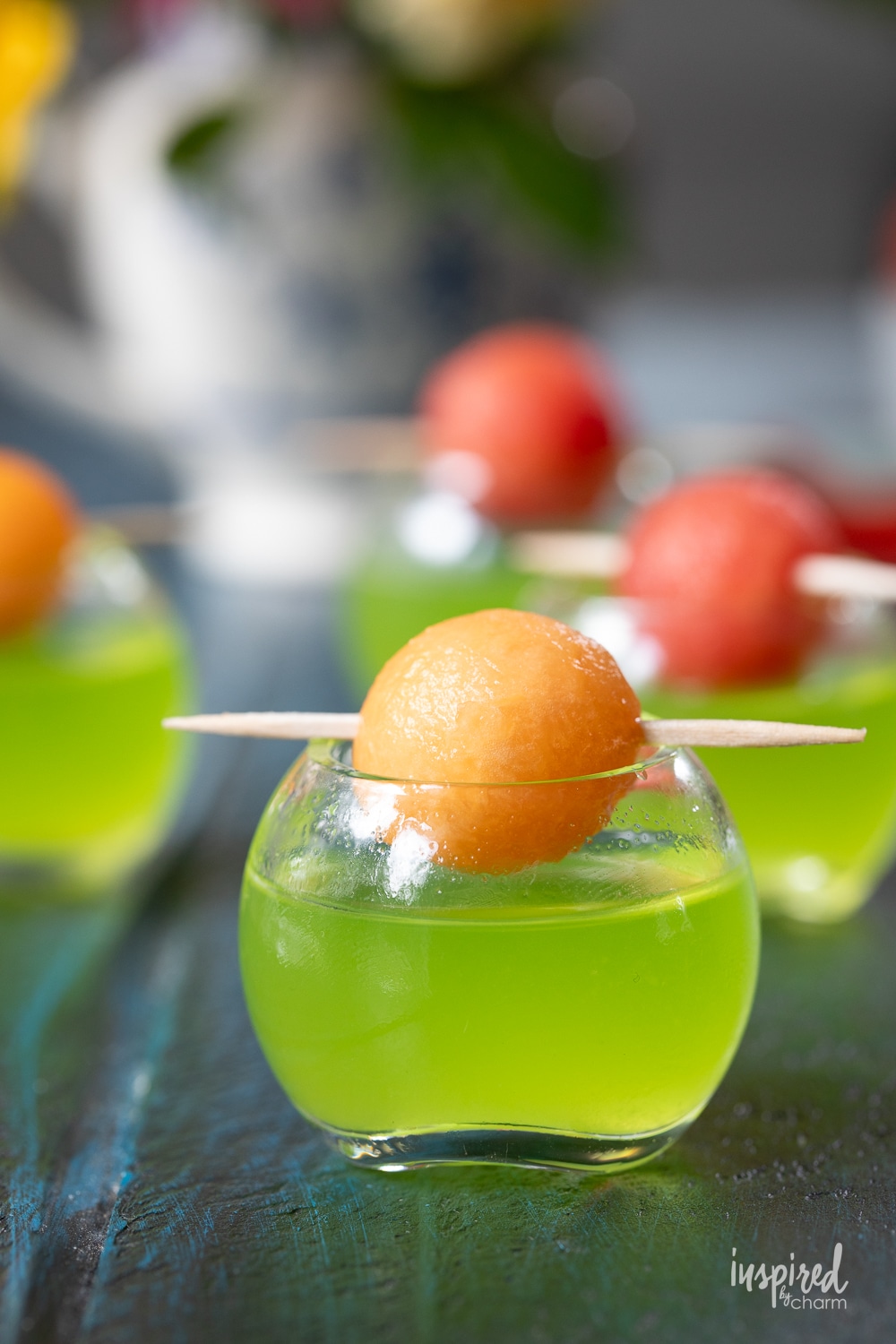 close up of a melon ball shot in a small round shot glass with melon ball garnish. 