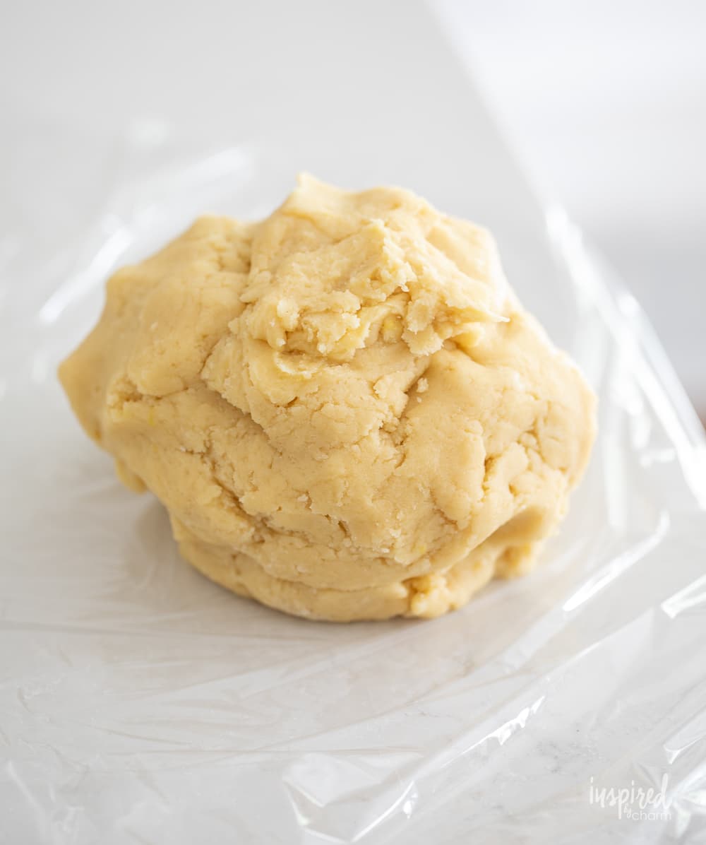 ball of lemon cookie dough on plastic wrap.