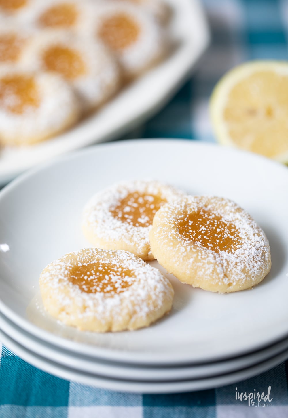 three lemon curd cookies on a stack of small white plates.