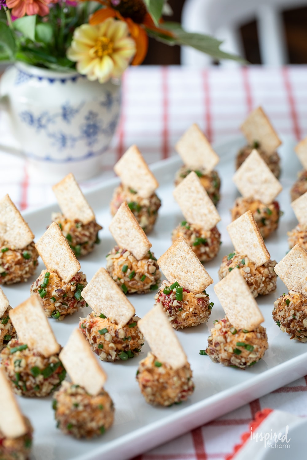 mini pimento cheese balls with crackers on a white serving plate.