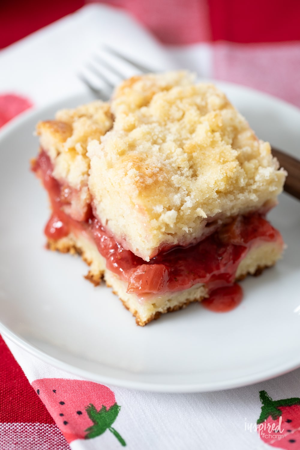strawberry rhubarb coffee cake with crumb topping.on a white plate.