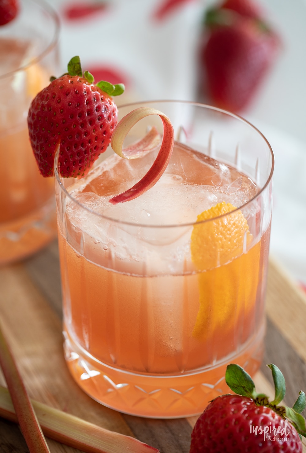 strawberry rhubarb old fashioned in a rocks glass served with strawberry and rhubarb garnish.