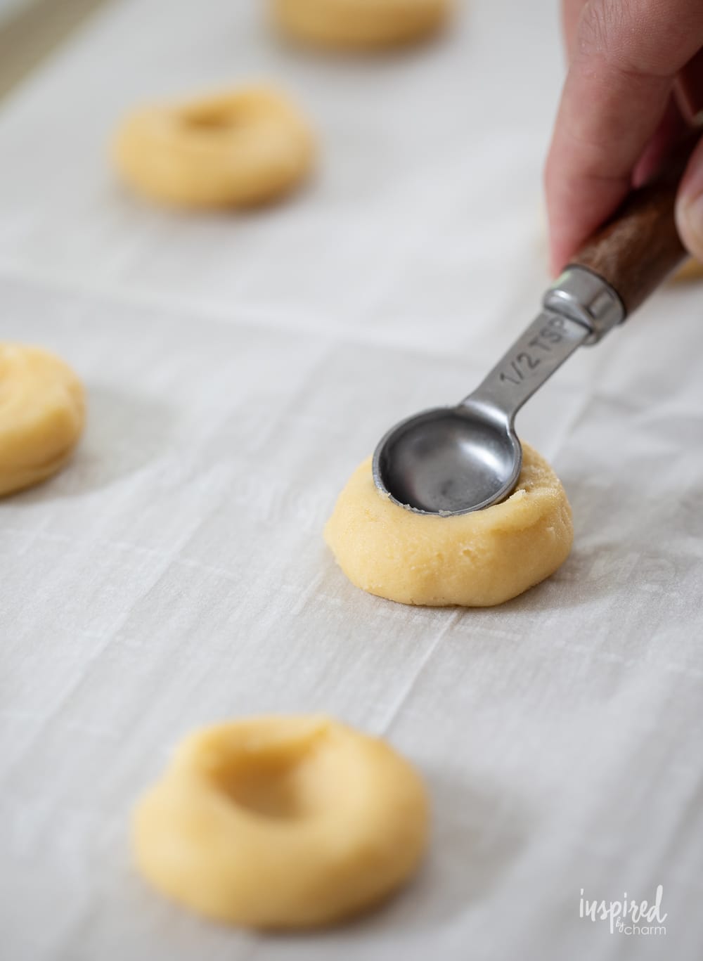hand pressing teaspoon into cookie dough. 