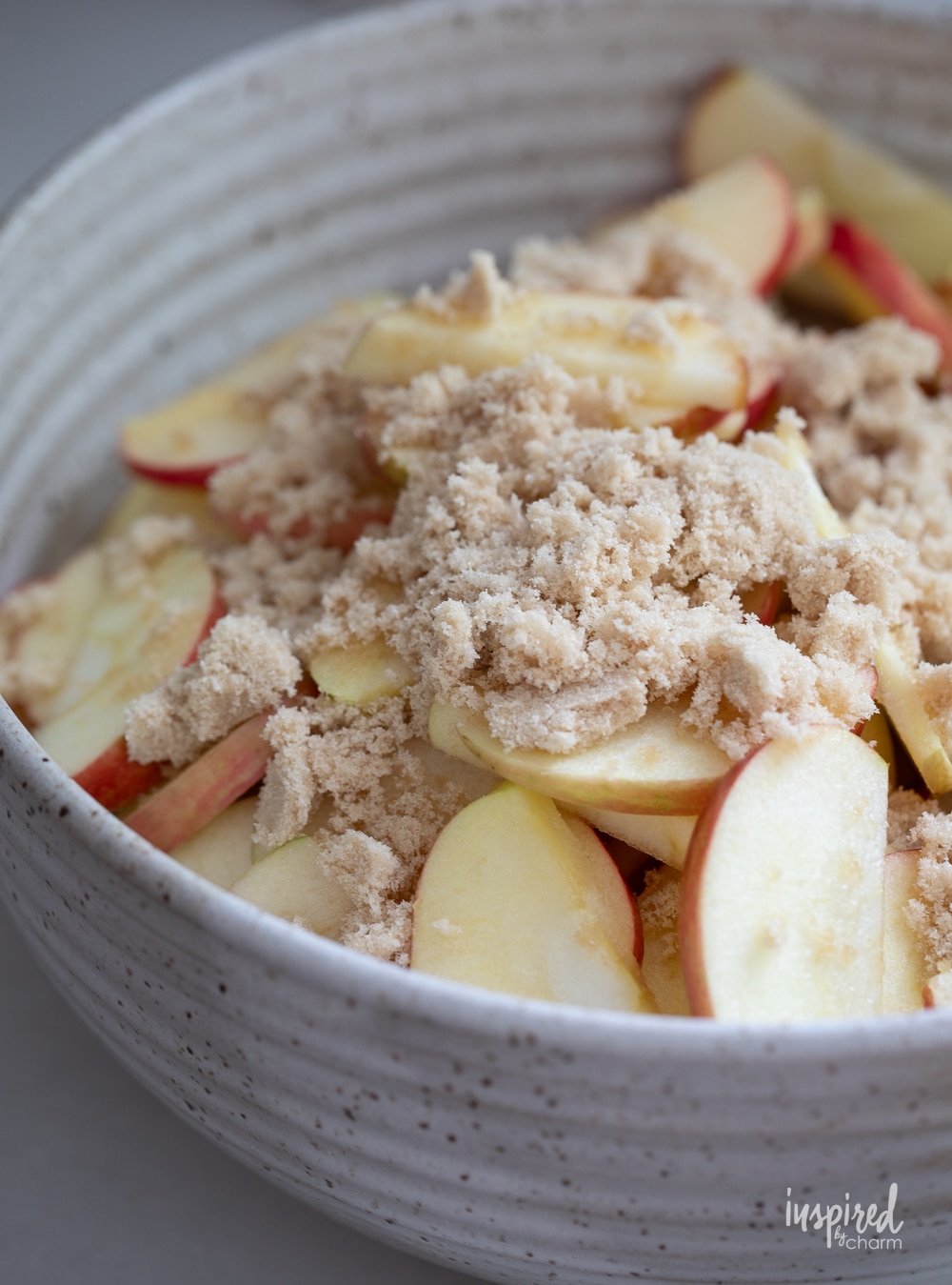 sliced apples in a bowl topped with brown sugar.