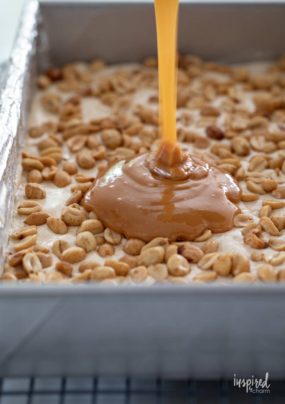 pouring caramel on a later of salted peanut bars.