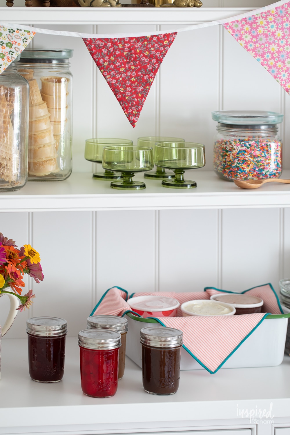 shelves filled with toppings, cones, and containers for an ice cream sundae bar.